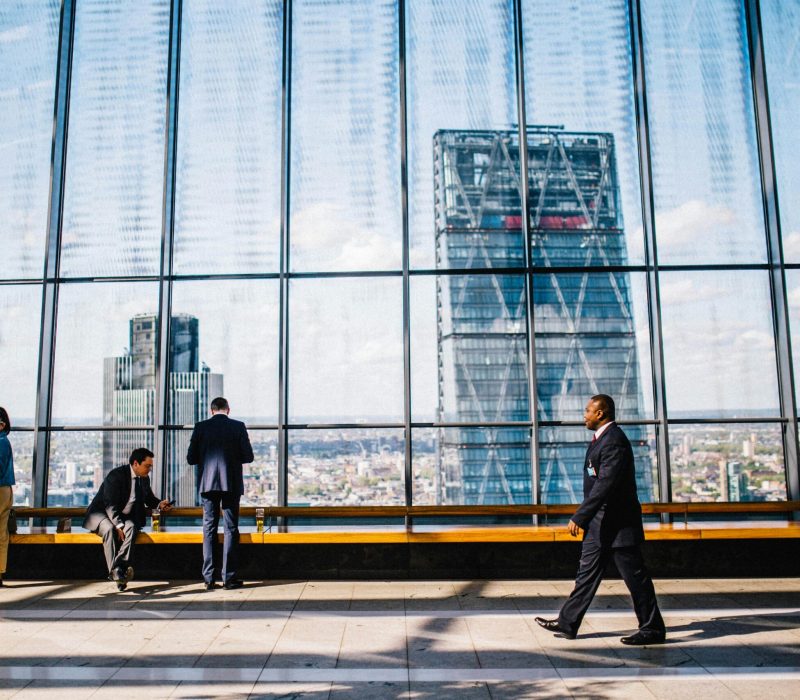 Business professionals in a modern office against a London skyline view.